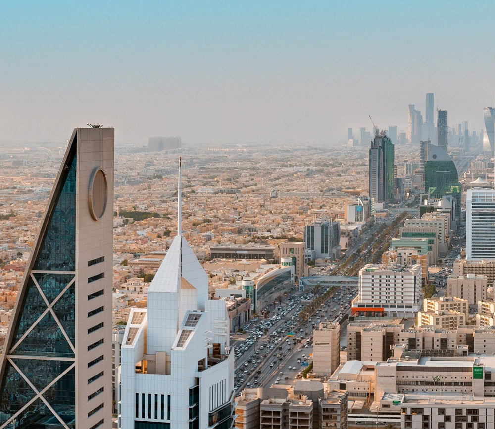 Aerial view of a modern cityscape featuring award-winning tall buildings, busy roads, and a clear sky.