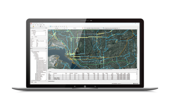Ekran laptopa wyświetlający szczegółową mapę systemu informacji geograficznej (GIS) z różnymi kolorowymi liniami i tabelami danych.