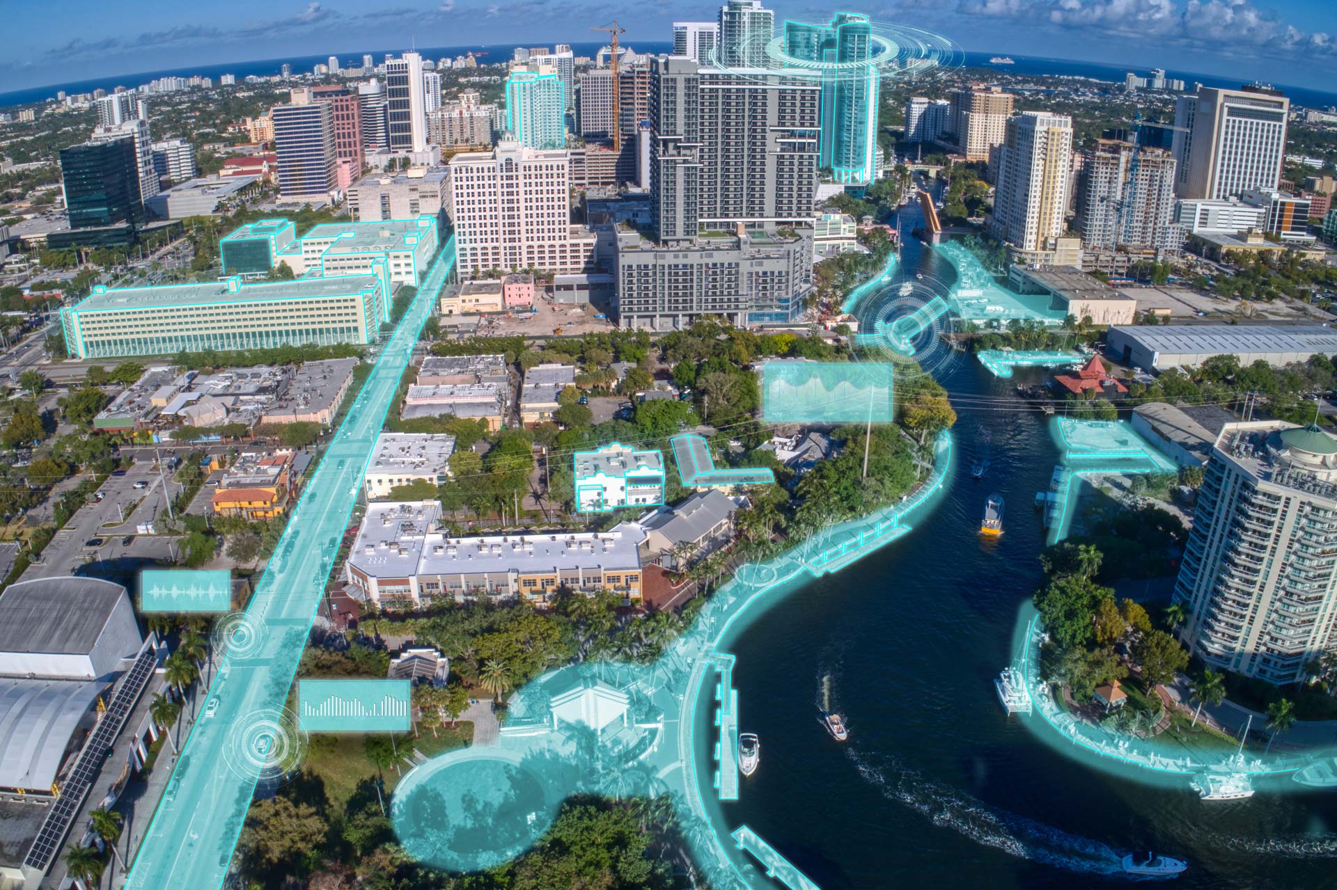 Aerial view of a city with a river running through it, featuring overlaid futuristic blue digital visuals highlighting key areas and buildings, presenting a visionary glimpse for MicroStation users in 2024.