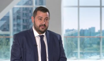 Man in a blue suit and tie presents at the CitiME Partner Spotlight event, set against a striking windowed cityscape backdrop, highlighting key developments in the Middle East.