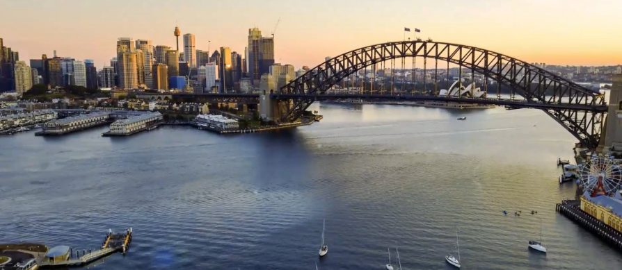 Aerial view of Sydney Harbour at sunset, showcasing the Sydney Harbour Bridge, Opera House, and city skyline with boats on the water. This stunning scene highlights Australia's beauty in a perfect Partner Spotlight moment.