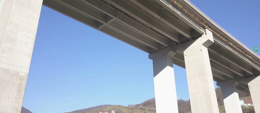 A view from beneath a tall concrete bridge with multiple support columns, set against a clear blue sky. Hills sprinkled with houses evoke the charm of Australia, creating a perfect Partner Spotlight backdrop.
