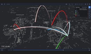 Mapa o ciemnym motywie wizualizująca dane śledzenia podróży z kolorowymi łukami reprezentującymi różne rodzaje aktywności pojazdu. Mapa pokazuje trasy i znacznik czasu w lewym dolnym rogu.