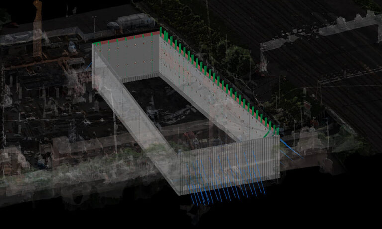 Modelo 3D de una obra subterránea con paredes rectangulares, vista desde arriba, rodeada de estructuras borrosas y vías férreas.