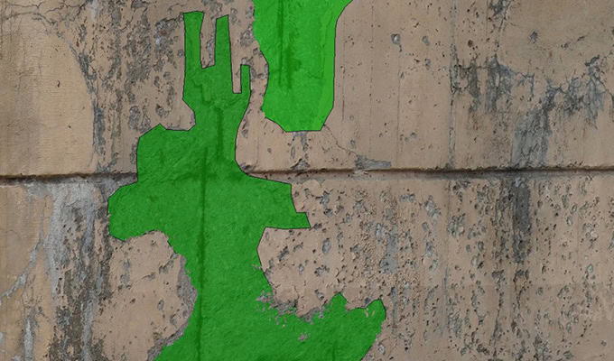 A weathered beige concrete wall with irregular bright green patches.
