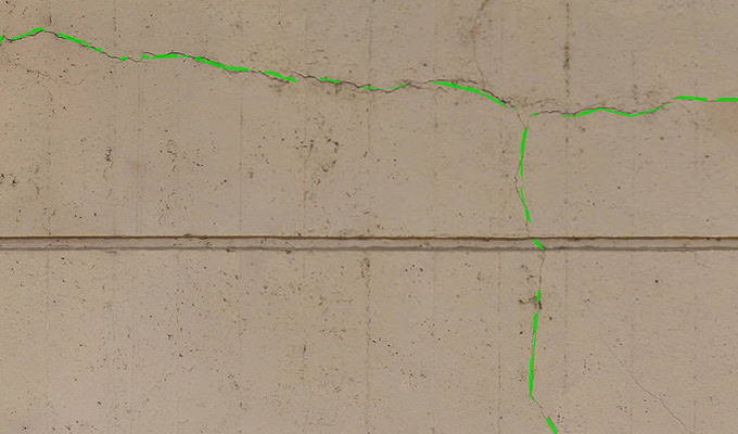 Concrete wall with visible cracks highlighted in green.