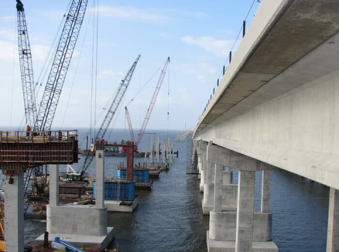 Construction in progress on a concrete bridge over a water mass