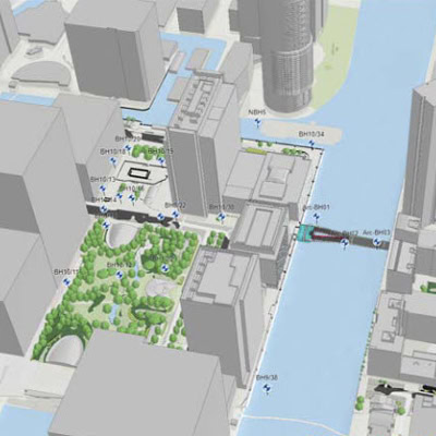 Une carte 3D d'une zone urbaine traversée par une rivière. Il y a plusieurs bâtiments, espaces verts et un pont traverse la rivière. Ces éléments ont été créés via une modélisation numérique détaille par Arcadis.