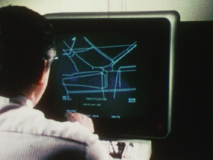 Personne travaillant sur un ordinateur dont l'écran noir affiche des lignes et des formes géométriques.