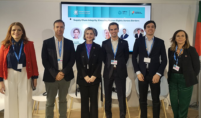 Six people standing in front of a screen displaying text about supply chain integrity and human rights.