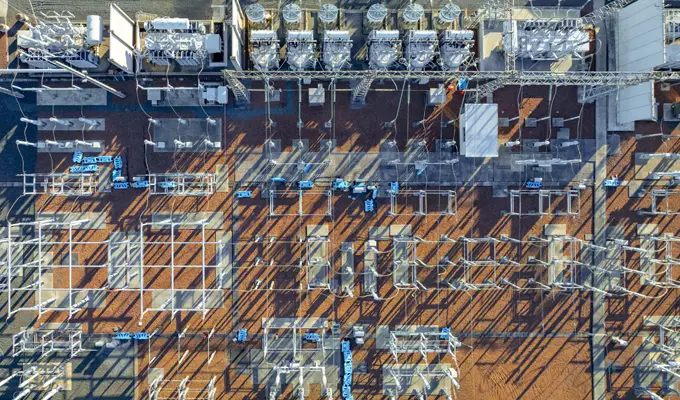 Aerial view of an electrical substation by HUBEI ELECTRIC, with transformers, wires, and equipment casting long shadows on the ground.