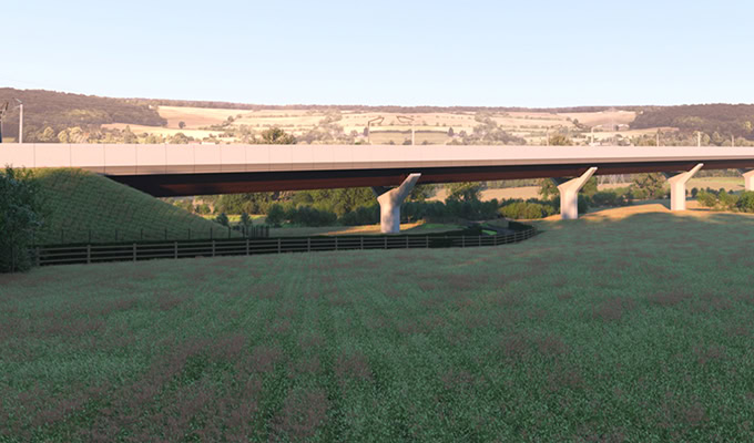 Uma ponte moderna se estende por um campo gramado com colinas distantes ao fundo sob um céu claro.