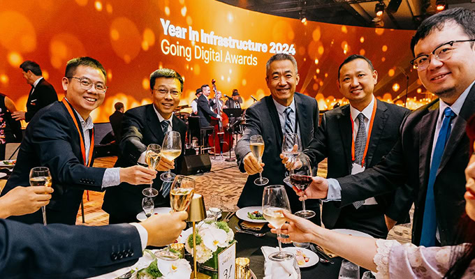 A group of people in formal attire raise their glasses in a toast at the "Year in Infrastructure 2024: Going Digital Awards" event.