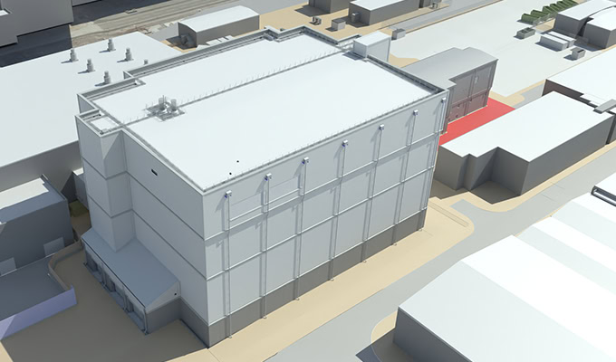 Aerial view of a large industrial building with a flat roof and multiple smaller structures surrounding it. The area appears to be an industrial or commercial zone.